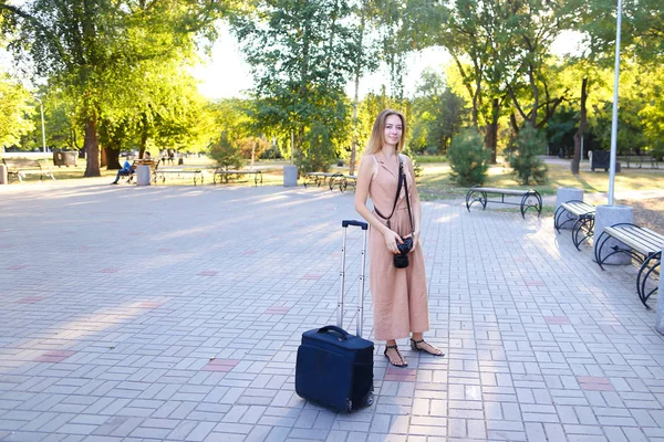 Молодий студент у сукні, що стоїть на вулиці з камерою та валізою . — стокове фото