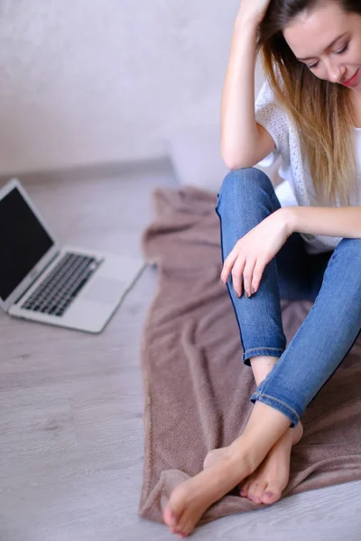 Estudiante sentada cerca de laptop y smartphone en la cama . — Foto de Stock