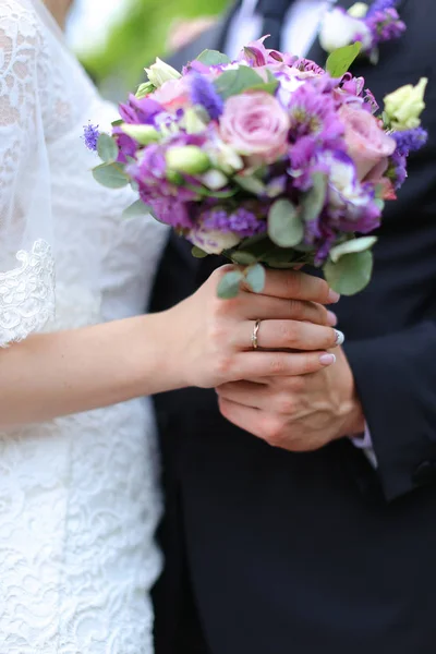 Closeup agradável buquê vioelt de flores em mãos de noivo e noiva . — Fotografia de Stock