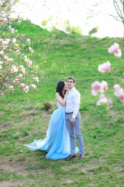 Mavi elbise giyen ve manolya erkek arkadaşı ile yakın yürüyüş genç kafkas kadın.