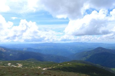 Arka planda bulutlar ile mavi ve yeşil Alp Dağları.
