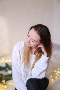 Yatakta çelenk ve sarı çelenk yakın oturan genç güzel kadın.