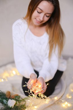 Parlayan sarı çelenk ve yeşil çelenk ile oturan genç kız.