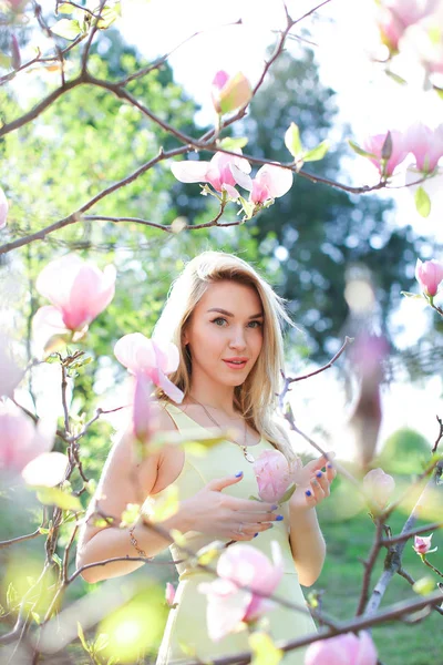 Ung glad kvinna som står nära magnolia i park. — Stockfoto
