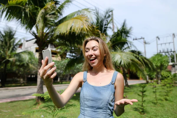 Palmiye ağaçları arka planda yakınındaki smarthone selfie yapma beyaz genç kız.