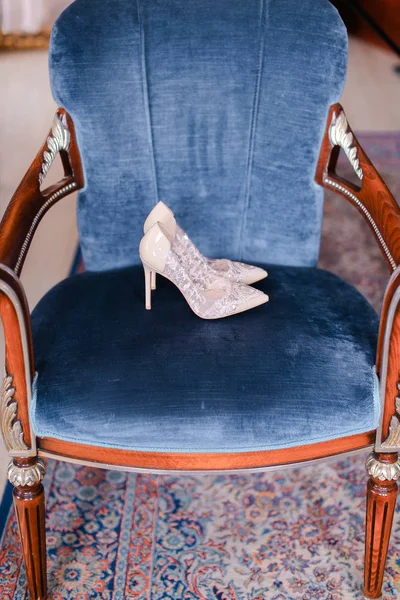 White bridal shoes on blue chair.