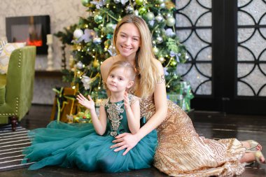 Genç Amerikalı anne ve küçük kızı bengal Noel ağacı yakınındaki katta oturan ışık ile.