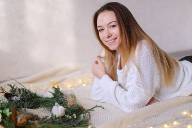 Genç Sarışın kadın yatakta yeşil çelenk ve sarı çelenk yakın yalan.