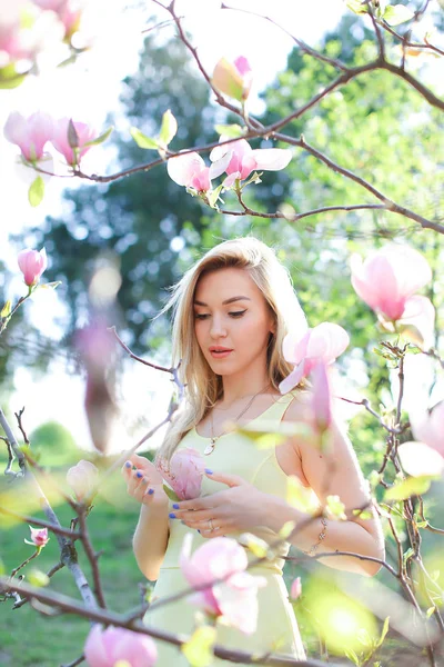 Unga kaukasiska kvinna som står nära magnolia i park. — Stockfoto