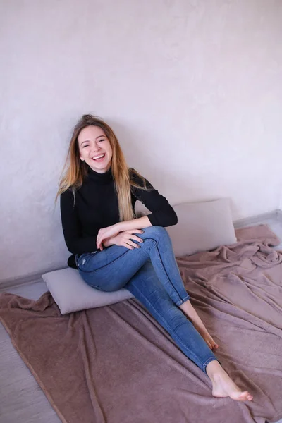 블랙 블라우스 앉아 벽 근처를 입고 웃는 소녀. — 스톡 사진