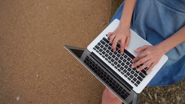 Slow motion student biolog tjej använder laptop skriva kurs arbete nära havet. — Stockvideo