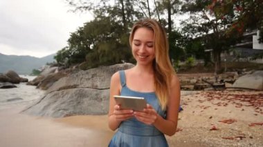 Ağır çekim iş kadını Malikânesi'nde sahil yakınında yürüyüş tablet kullanma