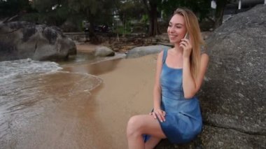 Ağır çekim modeli kız Smartphone cep telefonu ile deniz kenarında konuşma.