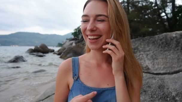 Señora gerente de recursos humanos de cámara lenta hablando en el teléfono inteligente en la orilla del mar sonriendo — Vídeos de Stock