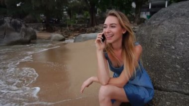 Ağır çekim dalgıç kız seaside kayaya oturan Smartphone cep telefonu ile konuşmak.