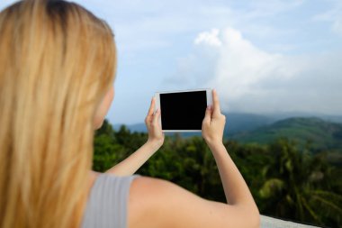 Tablet ve çekici fotoğraf Dağları arka planda kullanan genç sarışın kadın kişi.