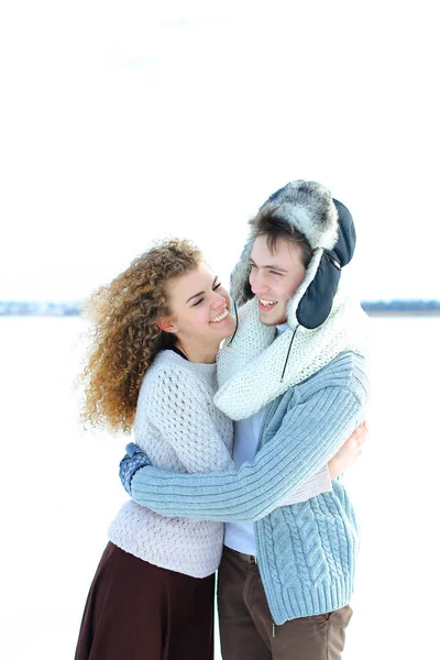 Menina abraçando menino vestindo chapéu de inverno e luvas no fundo de inverno . — Fotografia de Stock