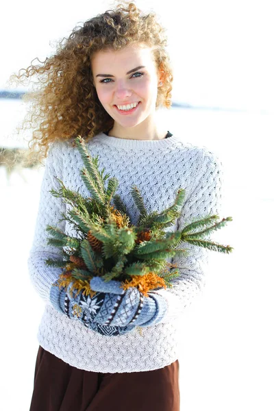 Mujer sonriente de pie con ramas de abeto en fondo blanco de invierno . — Foto de Stock