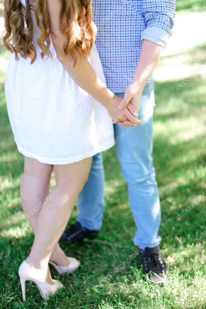 Closeup man and girl holding hands in grass background.