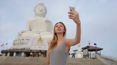 Ağır çekim modeli genç kadın selfies Smartphone Buddha yakınındaki s heykel Tayland alarak.