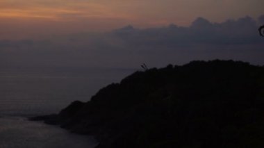 Ağır çekim çift günbatımı, oğlan ve kız akşam deniz kenarında yürüyüş zevk. Turizm, tatil yakın deniz ve seyahat kavramı. Dağ güzel deniz manzarası ile pastel gökyüzünün koyu bitkiler