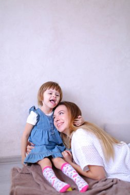 Küçük kızını sarılma ve yatağın üstüne oturan genç anne.