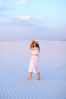 Kum üzerinde yürüyüş şapka ve beyaz elbise giyen kadın genç güzel