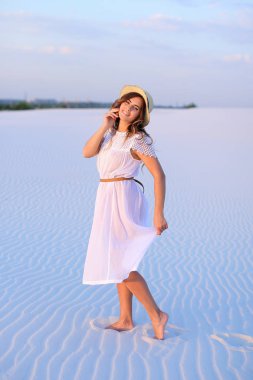 Bareffot kum, weaaring beyaz elbise üzerinde yürüyen Genç Sevimli kız bir