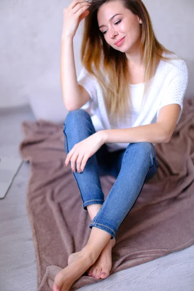Beyaz t giyen genç kız yatak, oturma — Stok fotoğraf