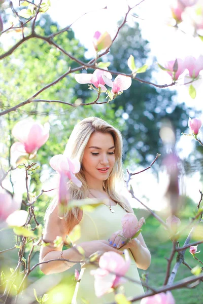 Unga europeiska kvinna som står nära magnolia i park. — Stockfoto