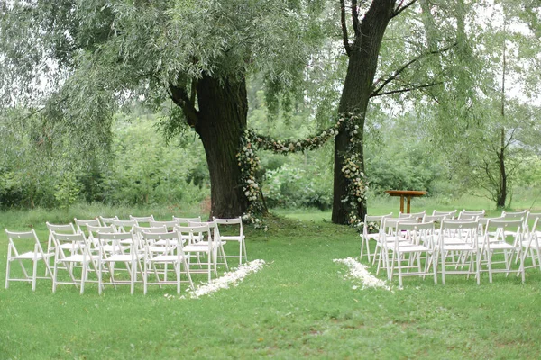 Arco de flores tierno para bodas y sillas blancas en el parque . — Foto de Stock