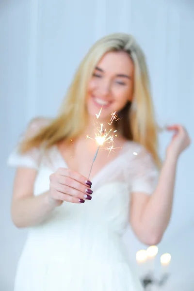 Loira feliz mulher mantendo bengala luz e vestindo vestido branco . — Fotografia de Stock