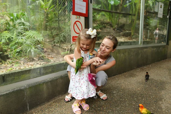 젊은 백인 어머니와 작은 딸 태국에서 밖에 서 앵무새와 함께 즐기는. — 스톡 사진
