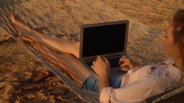 Повільна письменниця руху дама працює на ноутбуці, що лежить на гамаку — стокове відео
