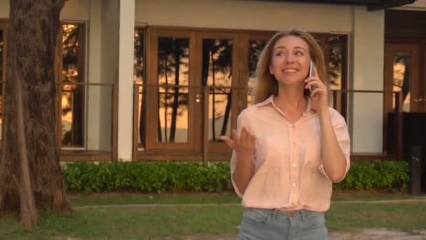 Menina economista em câmera lenta falando no smartphone andando perto do hotel — Vídeo de Stock