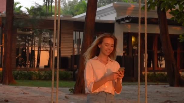 Slow motion future teacher female texting with boyfriend near summer cottage — Stock Video