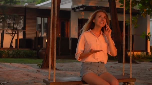 Ağır çekim öğrenci gazeteci Bayan yazlık yakınındaki salıncak üzerinde smartphone ile — Stok video