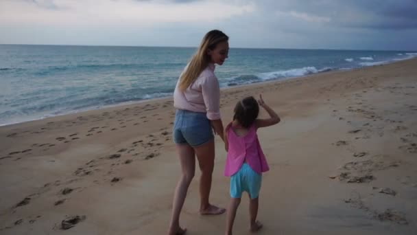 Lento movimento mãe e filhinha andando perto do mar à noite — Vídeo de Stock
