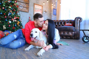 Öpüşme kadın ile Noel ağacı yakınındaki beyaz köpek yerde yatarken, dostum.