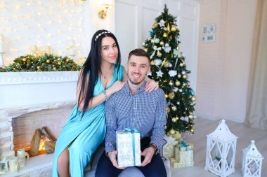 Genç kadın ve mevcut ile şömine ve Christas ağacının yakınında oturan adam.