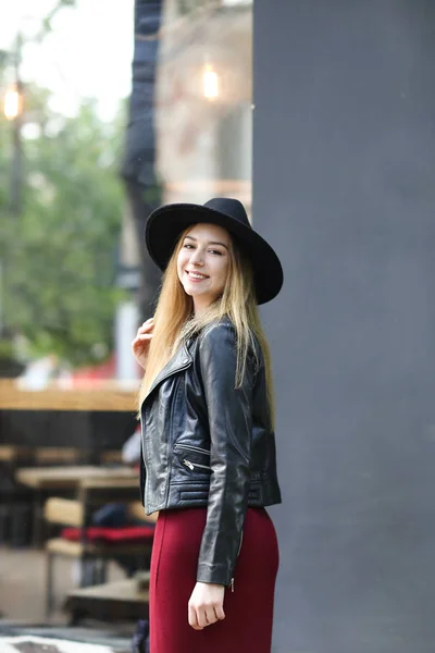 검은 모자와 빨간 드레스와 가죽 재킷을 입고 젊은 백인 여자. — 스톡 사진