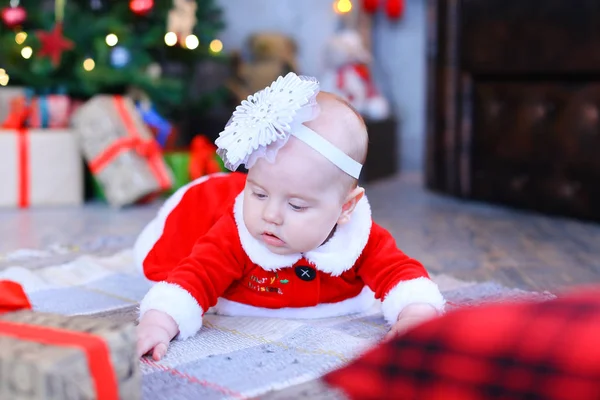 Blanc bébé femelle couché sur le sol près de l'arbre de Noël et présente . — Photo