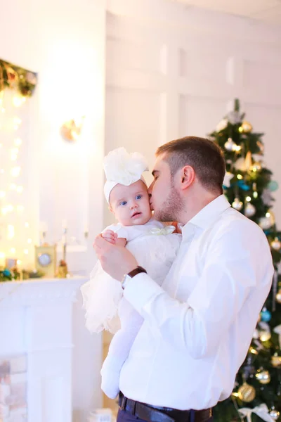 Jovem pai beijando pouco bebê feminino perto da árvore de Natal . — Fotografia de Stock