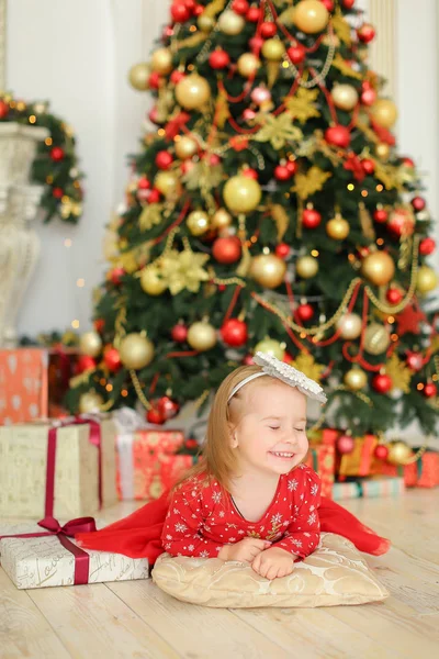 Pequeña bebé hembra tendida en el suelo cerca del árbol de Navidad y regalos lindos . — Foto de Stock