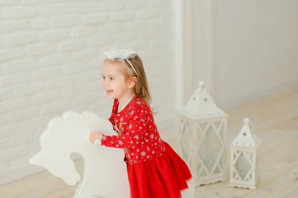 少女は赤いドレスを着て ロッキング ホース 白いレンガの壁バック グラウンドで遊んで ヴィンテージのおもちゃと幸せな子供の概念 — ストック写真