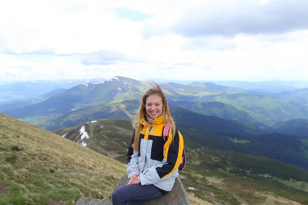Jovem turista caucasiana vestindo casaco amarelo sentado nas montanhas dos Cárpatos . — Fotografia de Stock