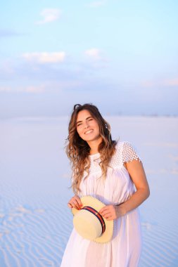 Ayakta beyaz elbise giyen şapka tutmak genç kadın kişi