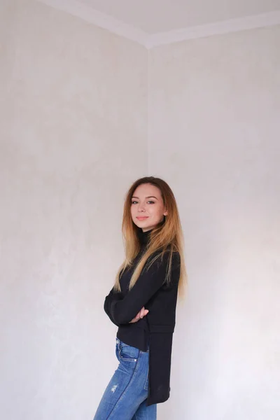 Young happy girl wearing black blouse standing near wall. — Stock Photo, Image