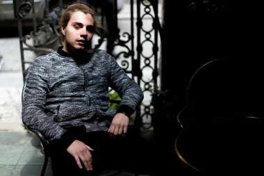 Kafede oturan gri kazak giyen genç adam.