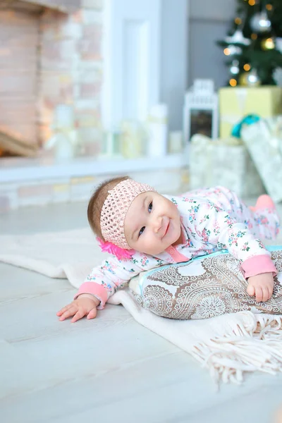 きらめくクリスマス ツリーとプレゼントの近くに毛布を床に横になっているきれいな女の赤ちゃん. — ストック写真